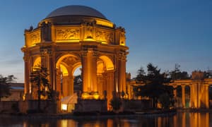 The Palace of Fine Arts rotunda glowing at blue hour, with an event tent beneath the illuminated arches