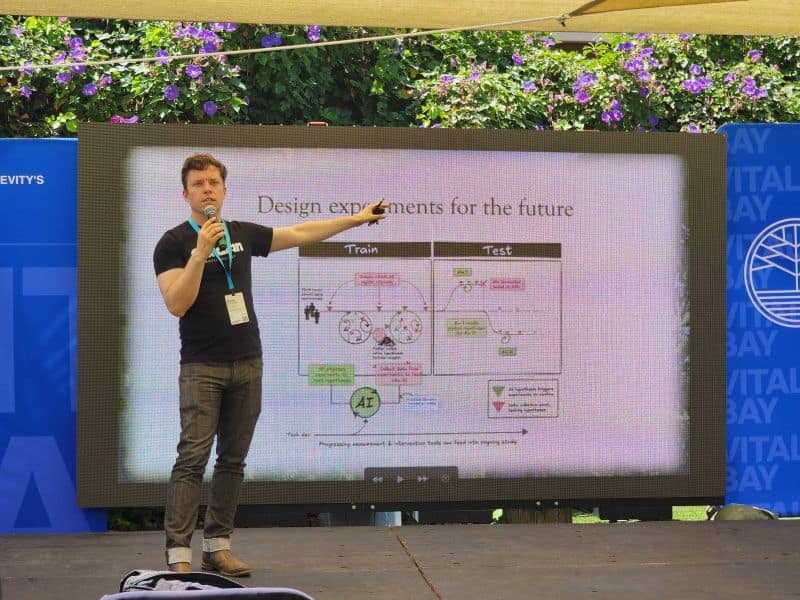 Martin Borch Jensen onstage at Vitalist Bay pointing to a slide titled Design experiments for the future